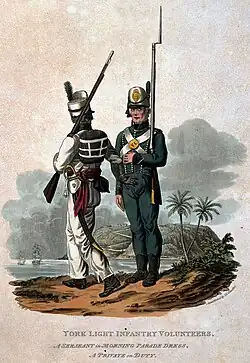 Two soldiers carrying weapons stand side-by-side, the one on the left facing away from the viewer and the one on the right facing towards them.
