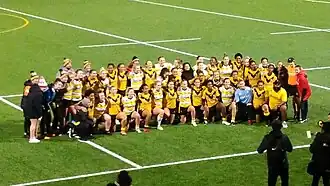 A group photo of two rugby league teams on a sports field