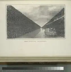 Canal boat traveling through canal with large earthen walls on either side